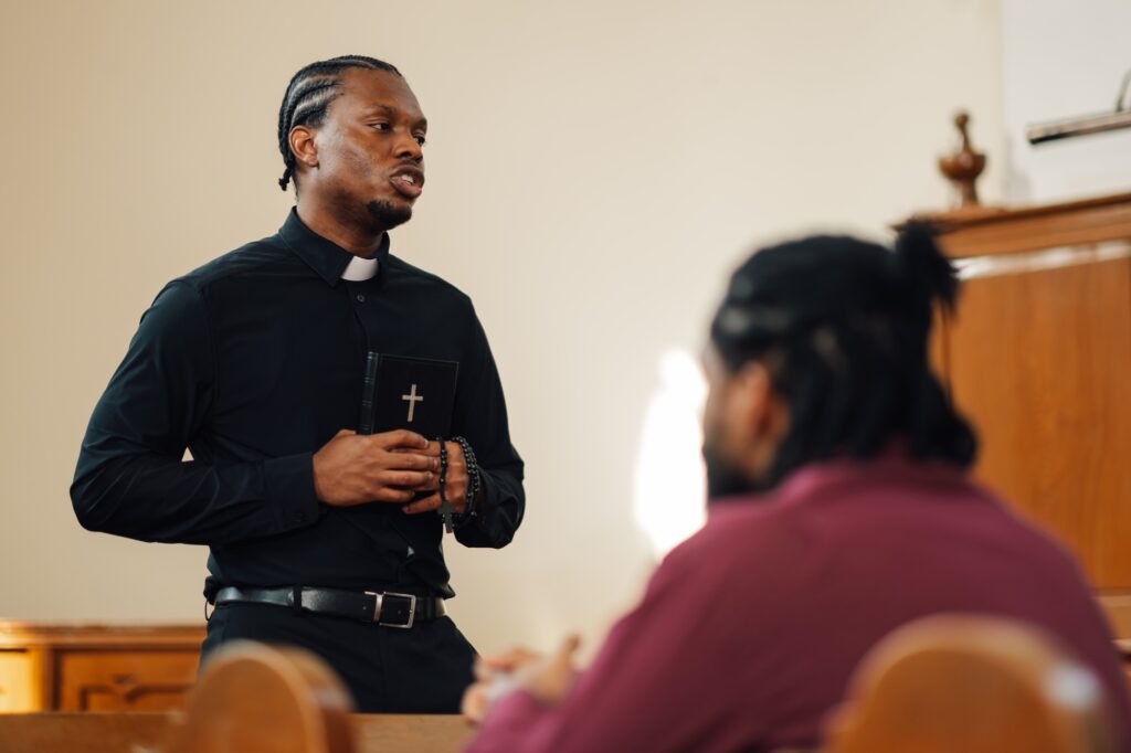 Young priest holding bible making eye contact during sermon