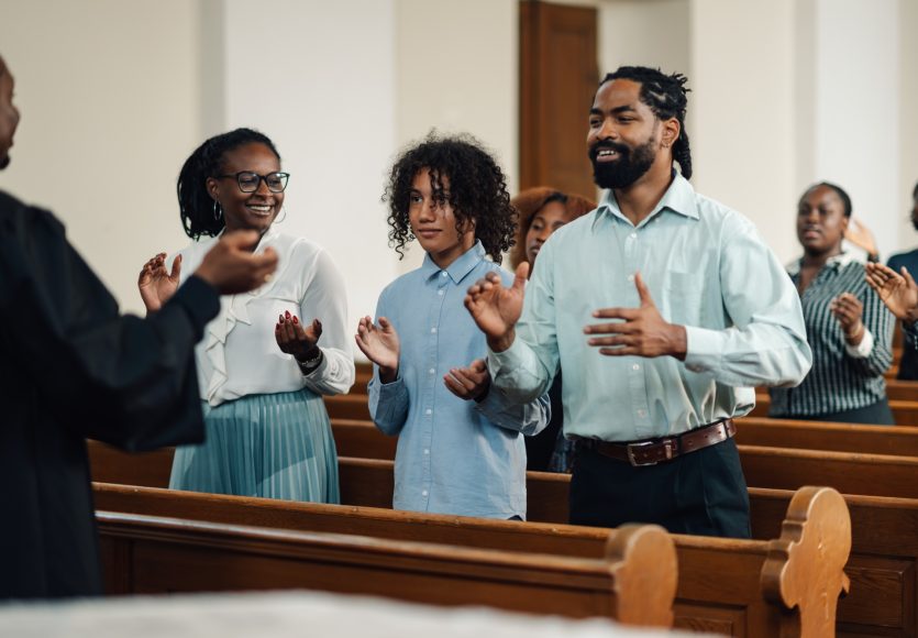 Group of people clapping and singing at a church service