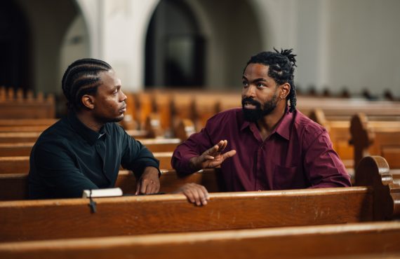 Two men having a serious conversation in church pews